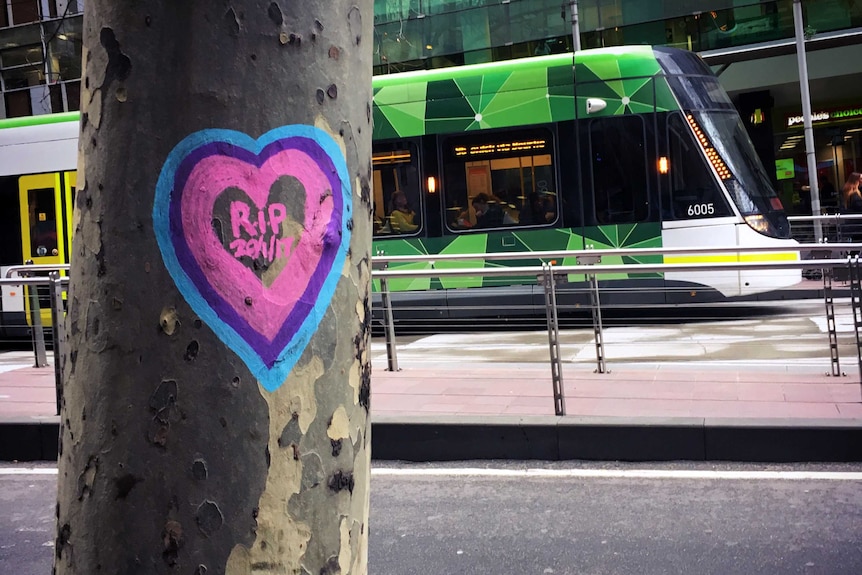 A colourful heart with 'RIP 20/1/17' is drawn on the trunk of a tree.