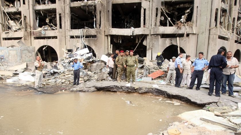 Iraqi army officers stand on the edge of a crater outside the destroyed Ministry of Justice building.