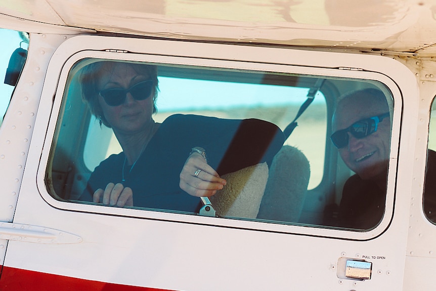 A man and woman smile in the cockpit of a light plane.