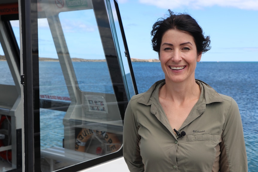 A woman named Erin Clitheroe stands aboard a boat smiling broadly.