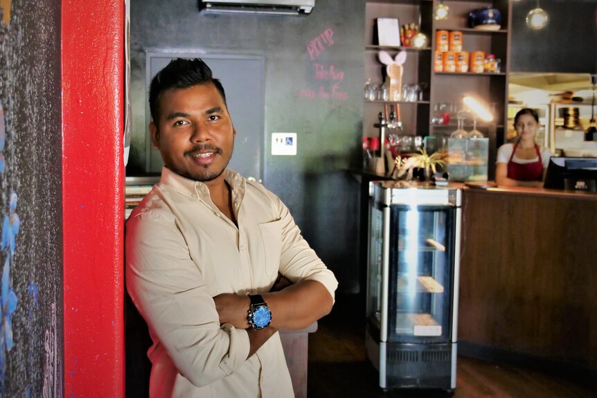 Bhairab leaning against a red pillar on a black wall looking at the camera inside a restaurant