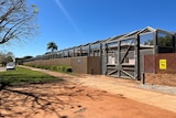 A large metal security gate and a high fence lined with barbed wire, stretching several metres.