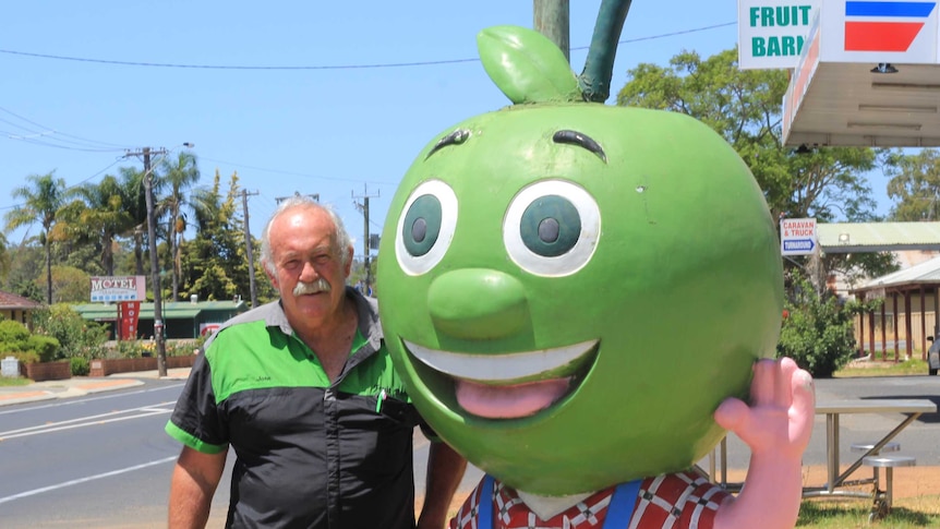 A man standing with an apple statue on a town's main street