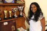 Soumiga Gopalakrishnan smiles as she stands beside some of the awards she had achieved at school.