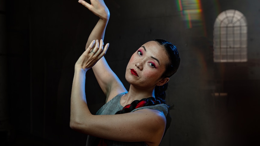 Rainbow Chan, a Chinese Australian in her 30s wears a silver dress and pink eyeshadow and looks wistfully at the camera.
