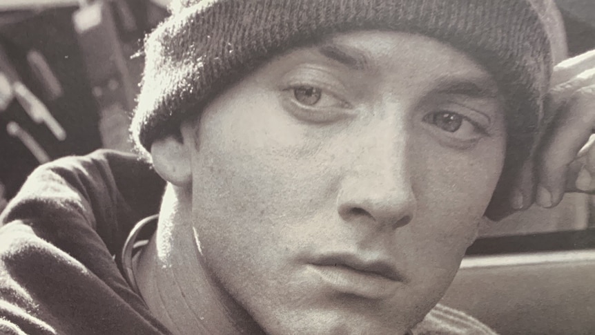 Eminem wears a beanie and a stern expression