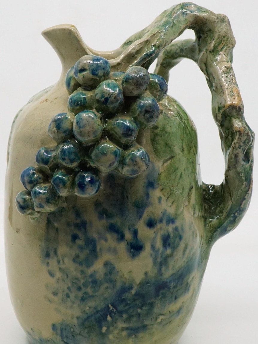a ceramic jug with grapes sculpted into the top
