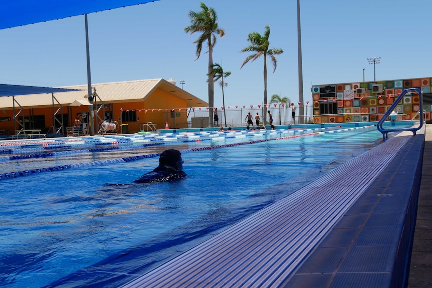 A man swimming in a public pool with lanes marked by ropes and floats Ausnew Home Care, NDIS registered provider, My Aged Care