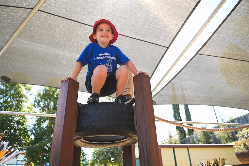 Hudson sits on a tyre smiling, about a metre off the ground.