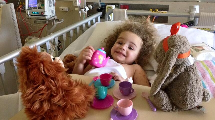 A young girl with toys in a hospital bed