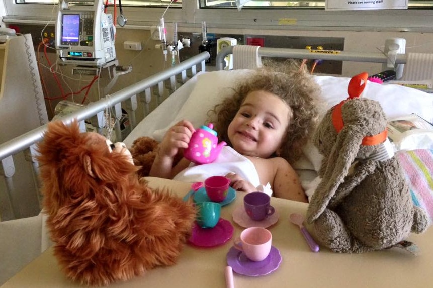 A young girl with toys in a hospital bed