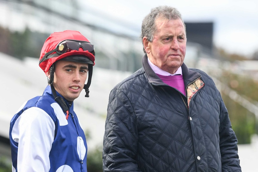 A jockey stands next to a trainer at Flemington Racecourse in Melbourne.