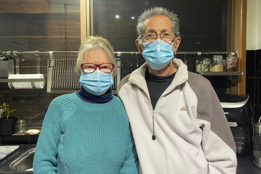 A woman and man stand next to each other in a kitchen.