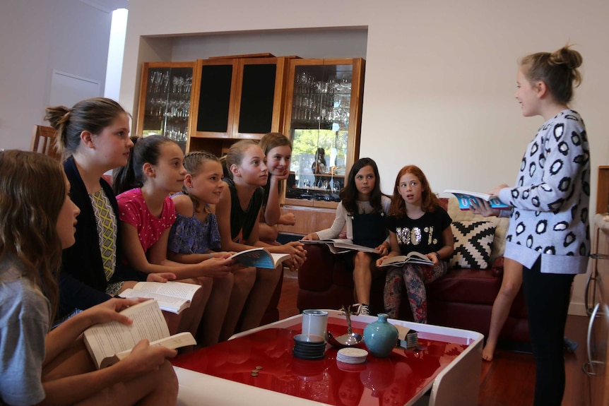 Girls sit in a lounge room discussing books