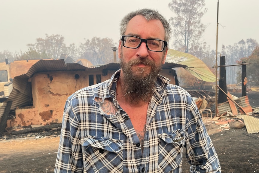 A man with a blank expression on his face looks at the camera.