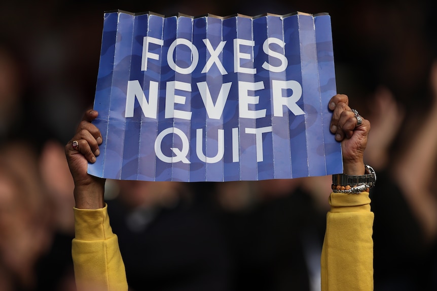A sign says Foxes never quit on blue card