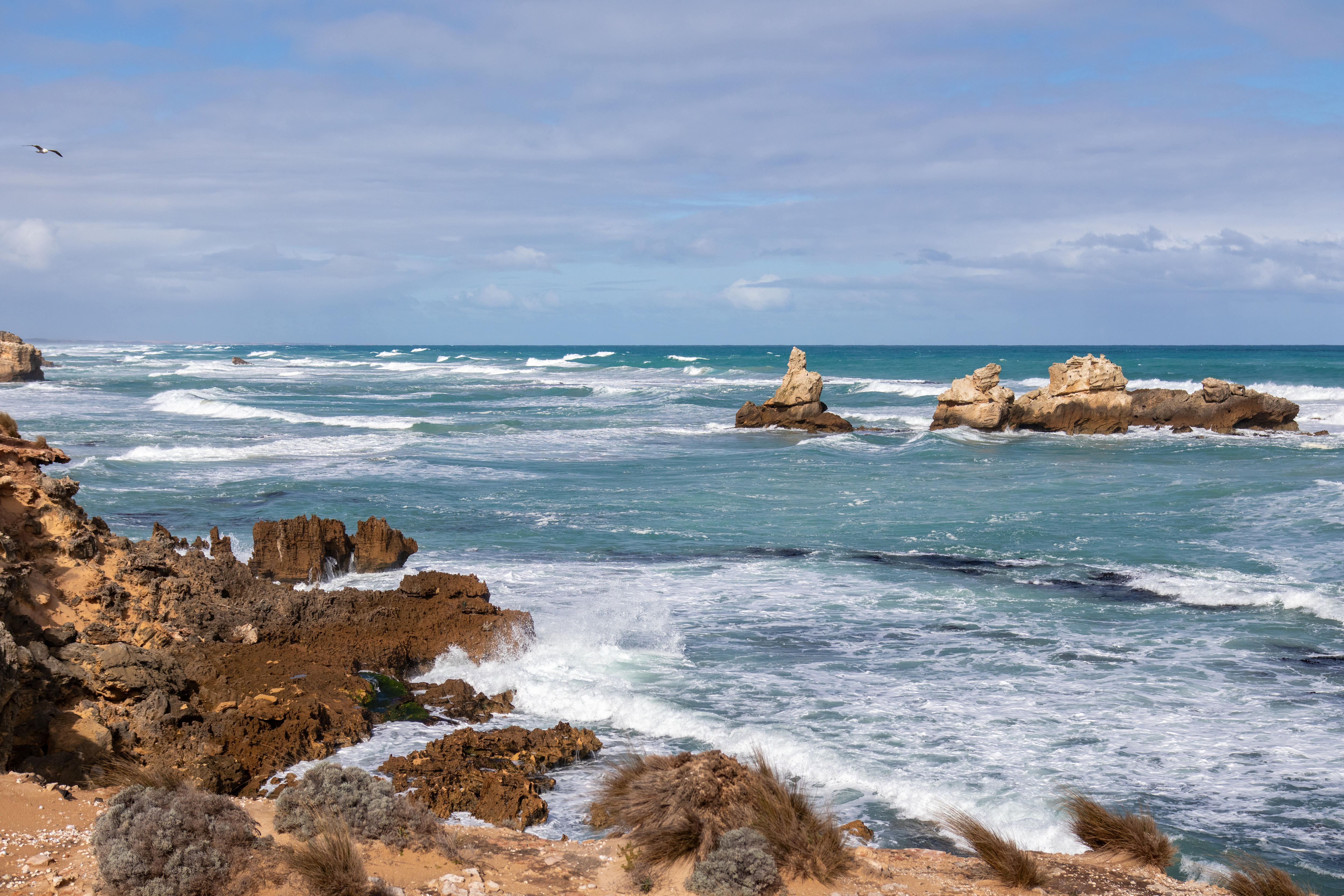 Olas blancas chocan contra acantilados rocosos