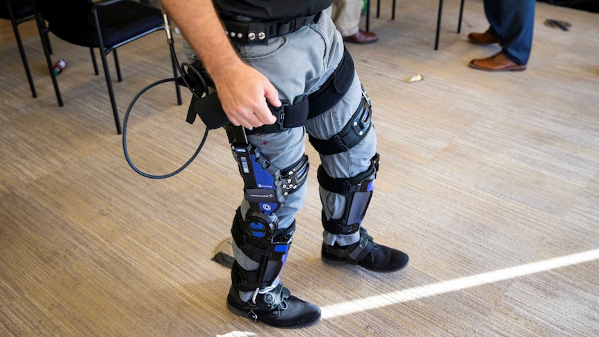 A man wearing a pair of jeans and a set of what appears to be legs braces equipped with technological elements
