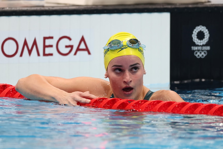 An Australian female swimmer leans on the lane rope at the end of a race.