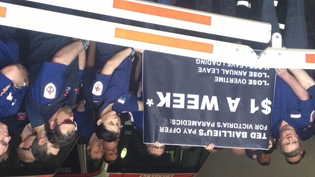 Paramedics at Royal Melbourne Hospital holding up sign