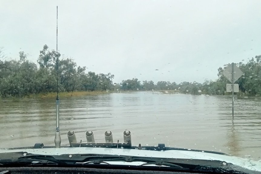 A photo taken from the driver's seat shows floodwaters across the road