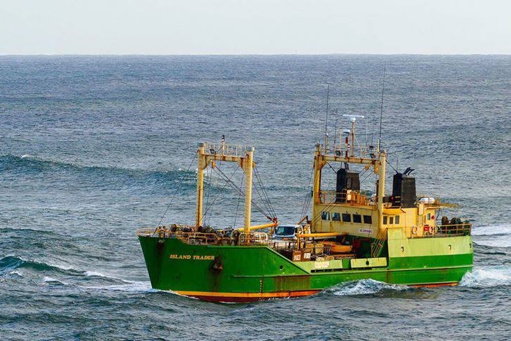Green and yellow ship travelling through the ocean