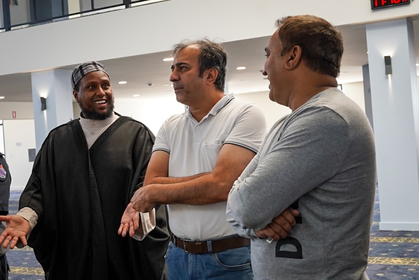 Imam Saeed Warsama Bulhan smiles as he chats to two men inside the mosque.
