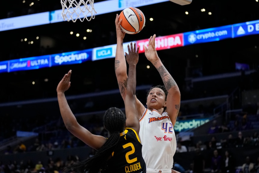 Wearing white, Brittney Griner vies for the ball in an NBA game