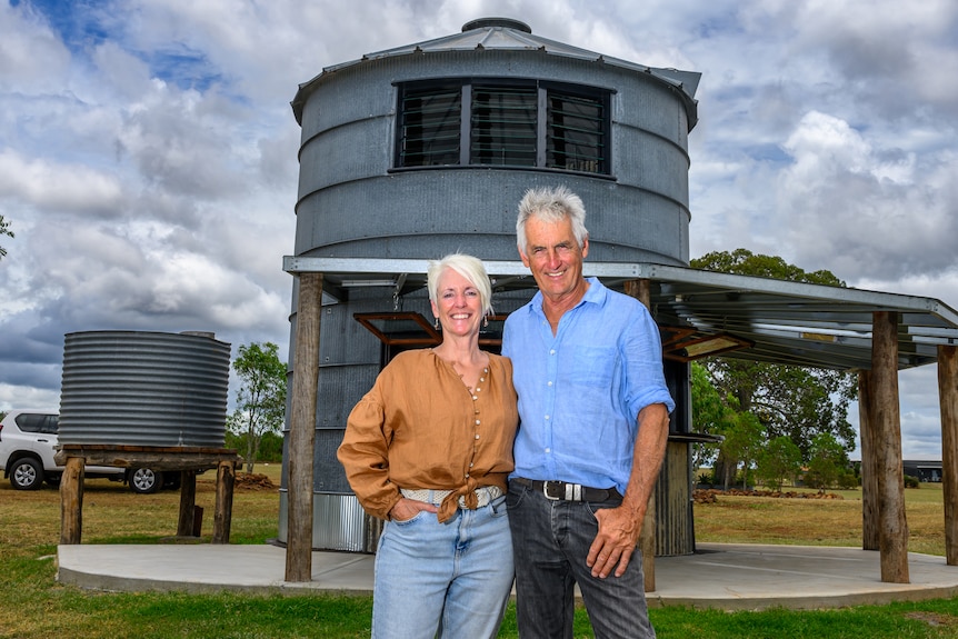 a man and woman smile in front of their silo