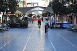 Two cyclists ride through an almost empty mall area in Bondi Junction during lockdown.
