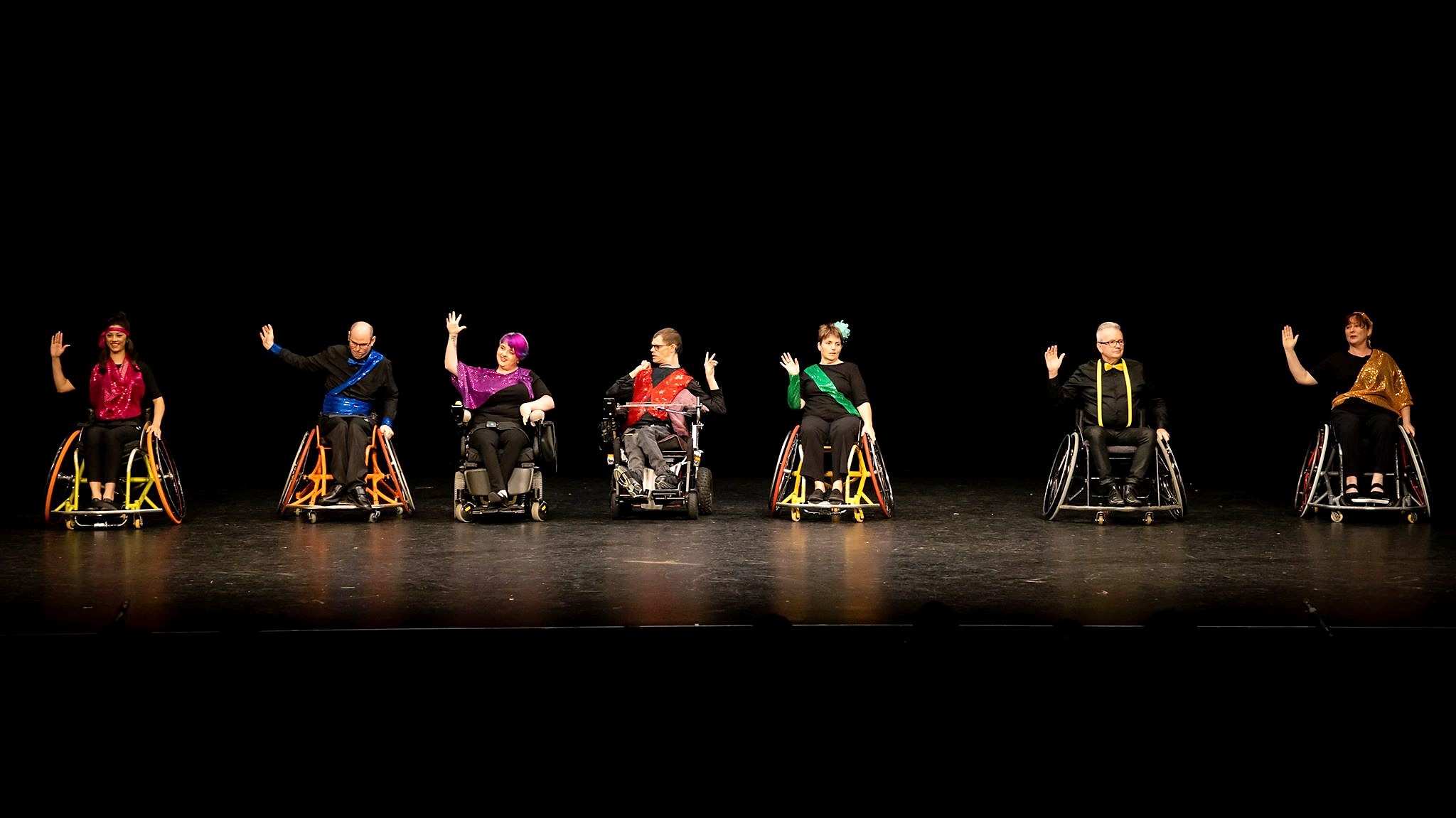 A group of wheelchair dancers performs on stage.