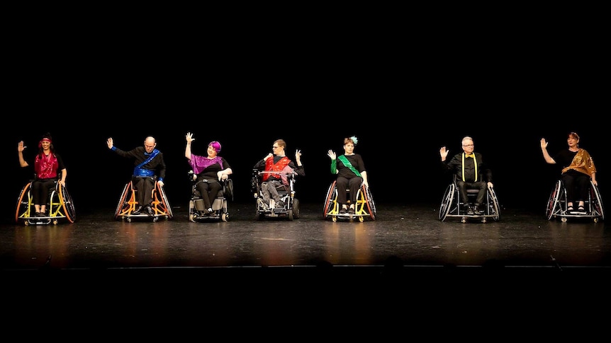 A group of wheelchair dancers performs on stage.