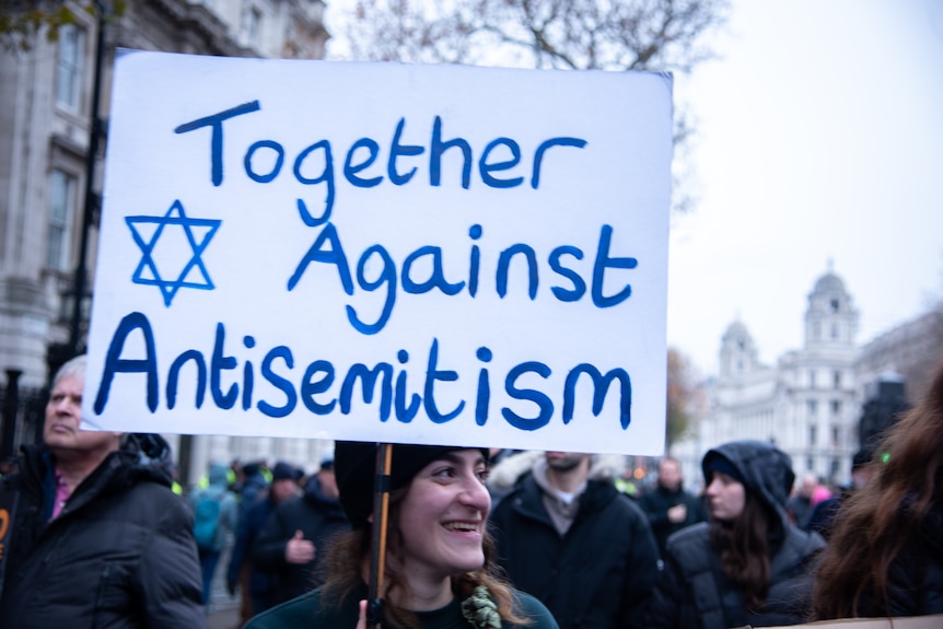 Woman holding sign that reads 'Together against anti-Semitism'