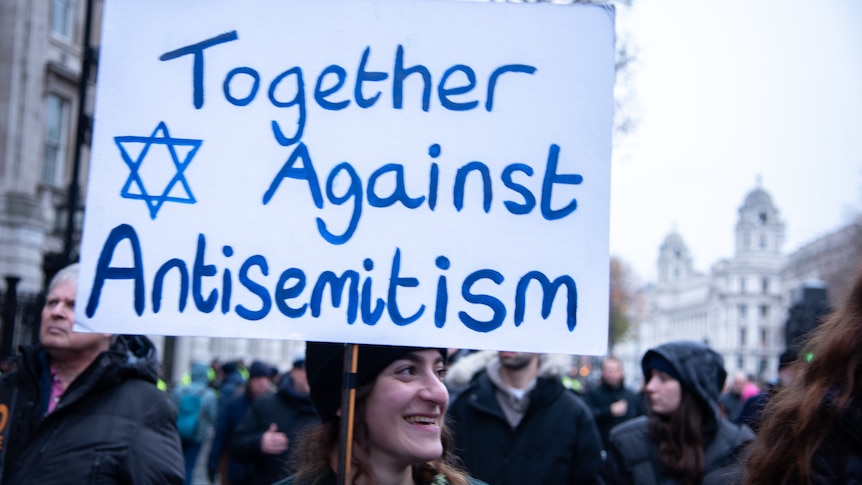 Woman holding sign that reads 'Together against anti-Semitism'