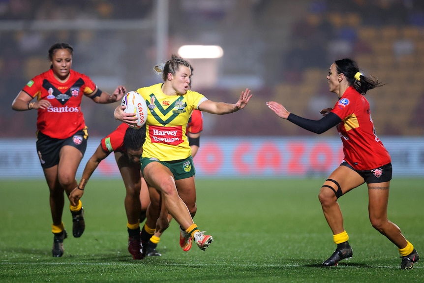 Australian Jillaroos player Emma Tonegato tries to fend off an run away from PNG defenders at the Rugby League World Cup.