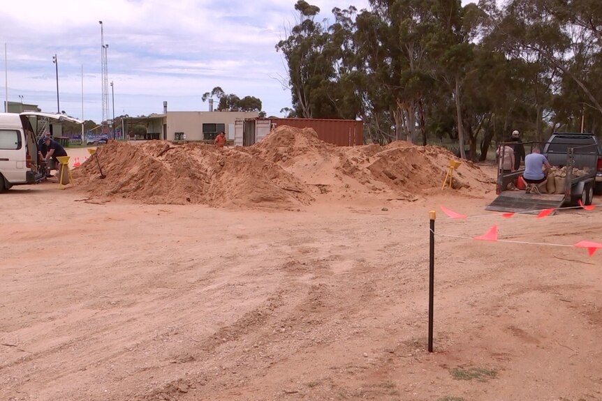 A large pile of sand with vehicles around it