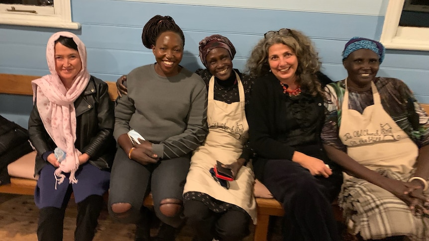 Five smiling people sitting on a couch