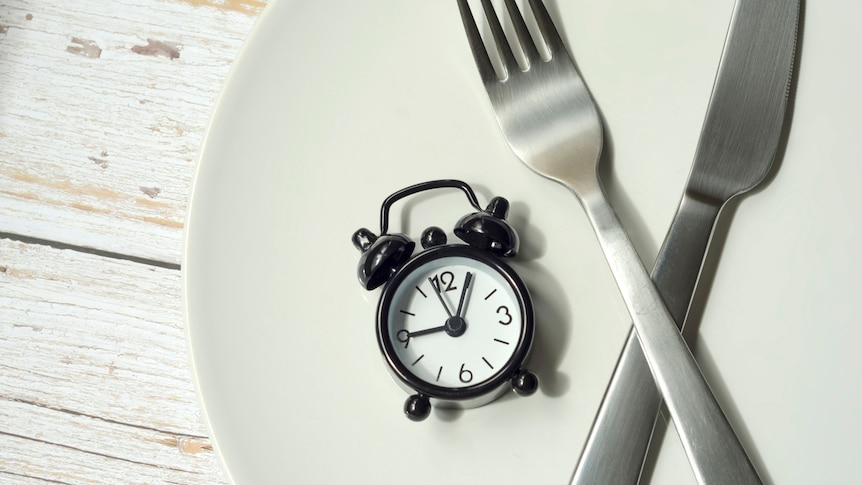 alarm clock alongside a knife and fork