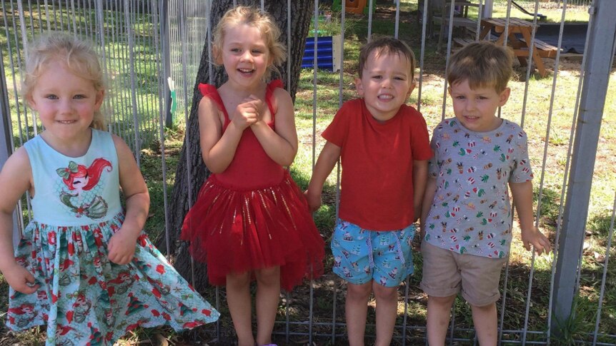 Four children pose for the camera at a playgroup near Newcastle.