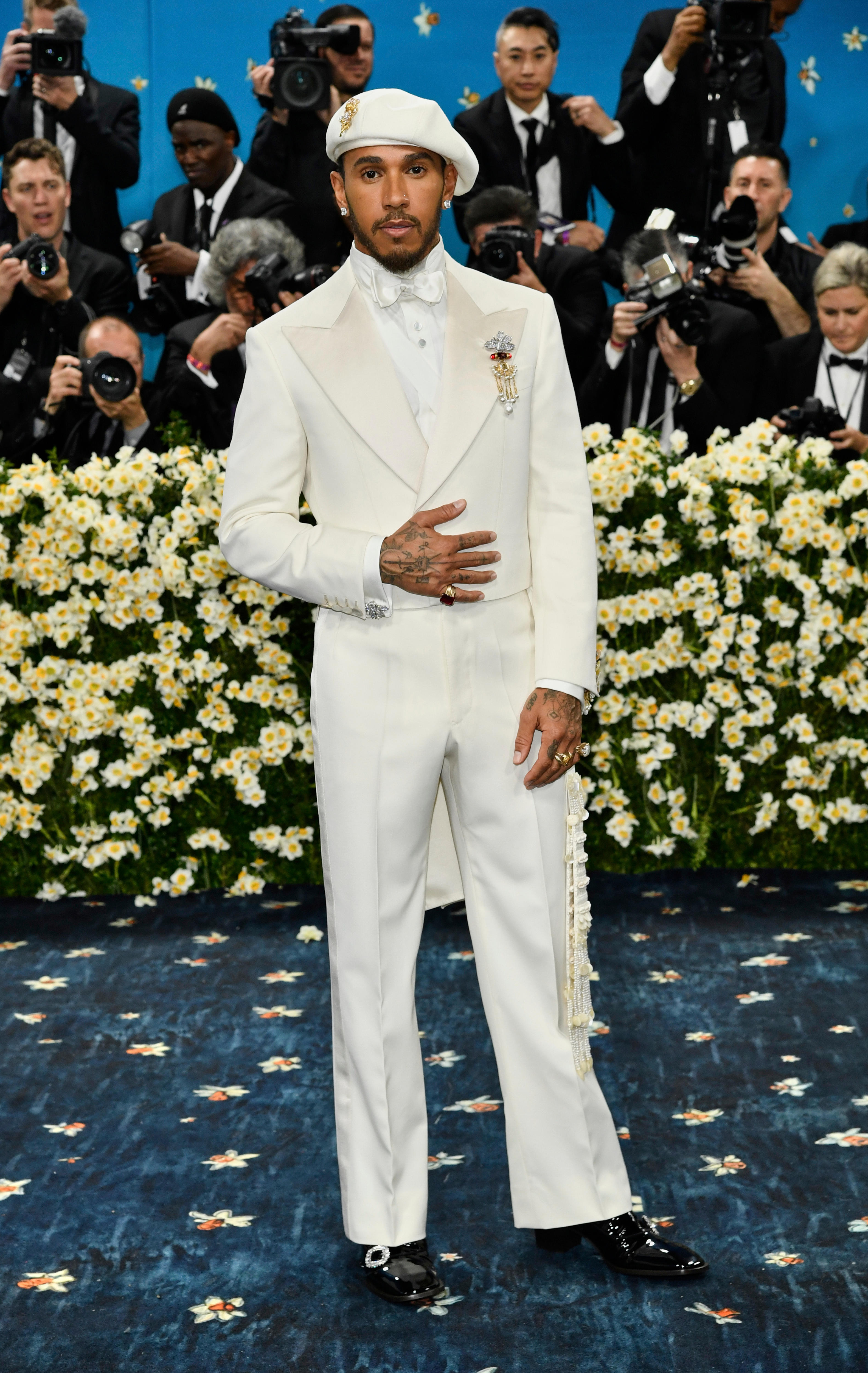  Lewis Hamilton wearing an all-white suit with a beret, a bow-tie and a dangly gold brooch 