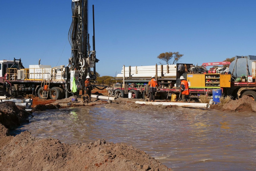 Trucks, a drilling machine and a pool of water