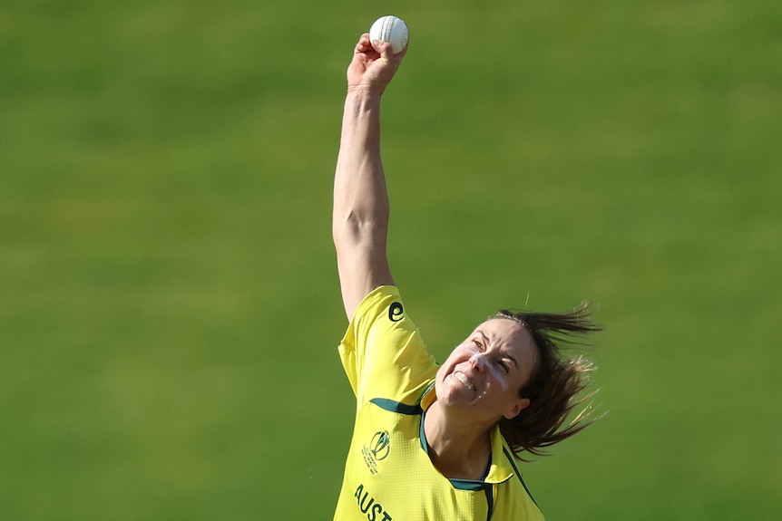 Ellyse Perry is shown mid bowling motion next to the stumps