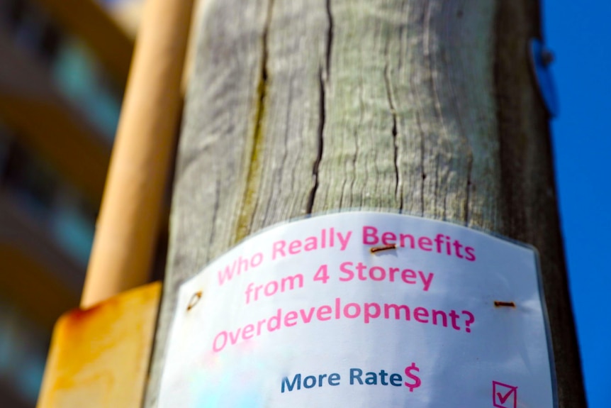 sign that reads who really benefits for 4 storey overdevelopment