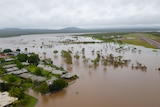 An aerial shot shows flood water surrounding a remote community