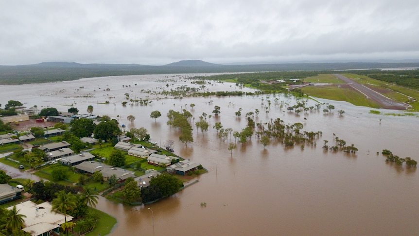 An aerial shot shows flood water surrounding a remote community