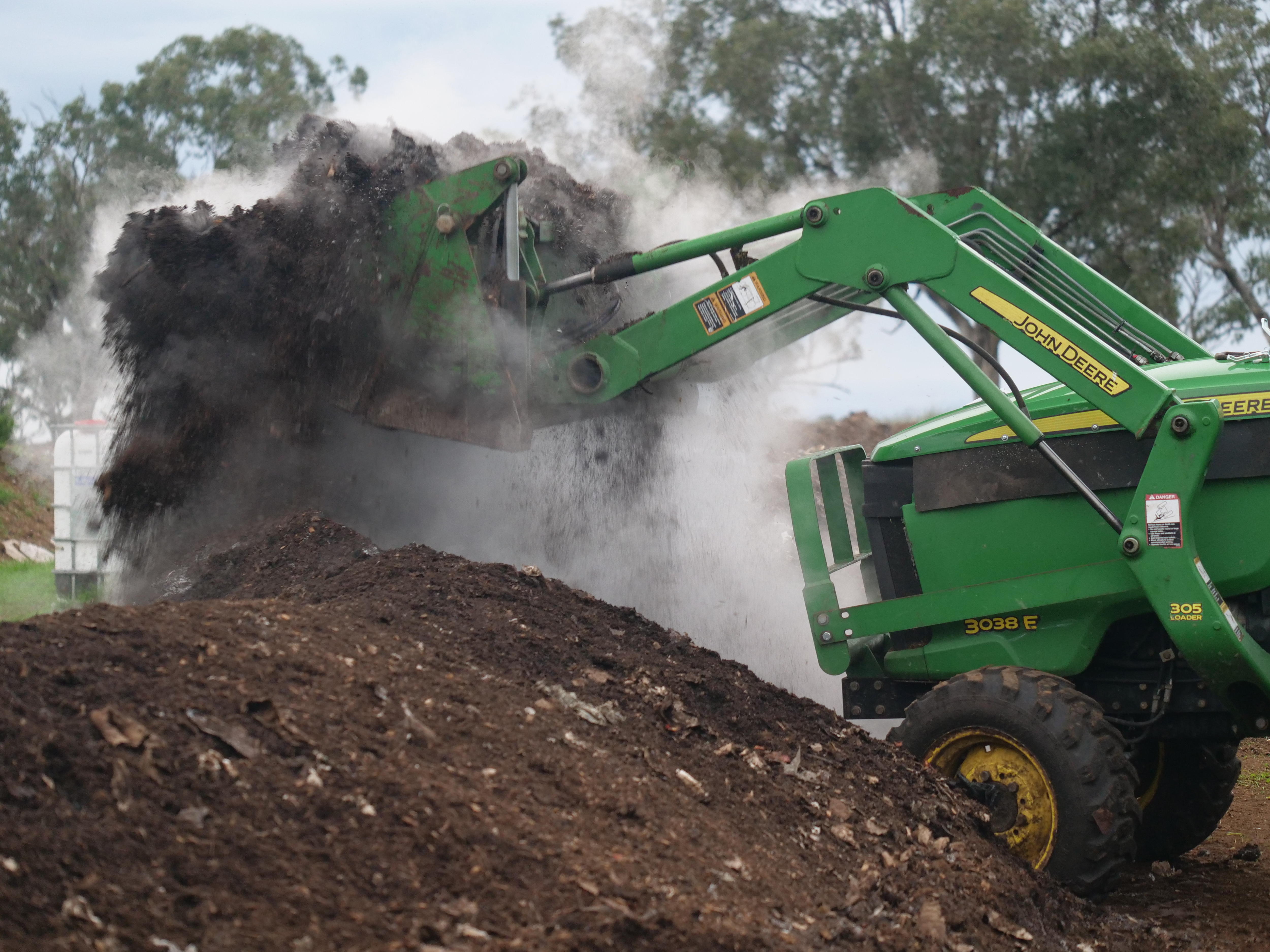 Un tractor levanta el abono permitiendo que escape una espesa nube de vapor.