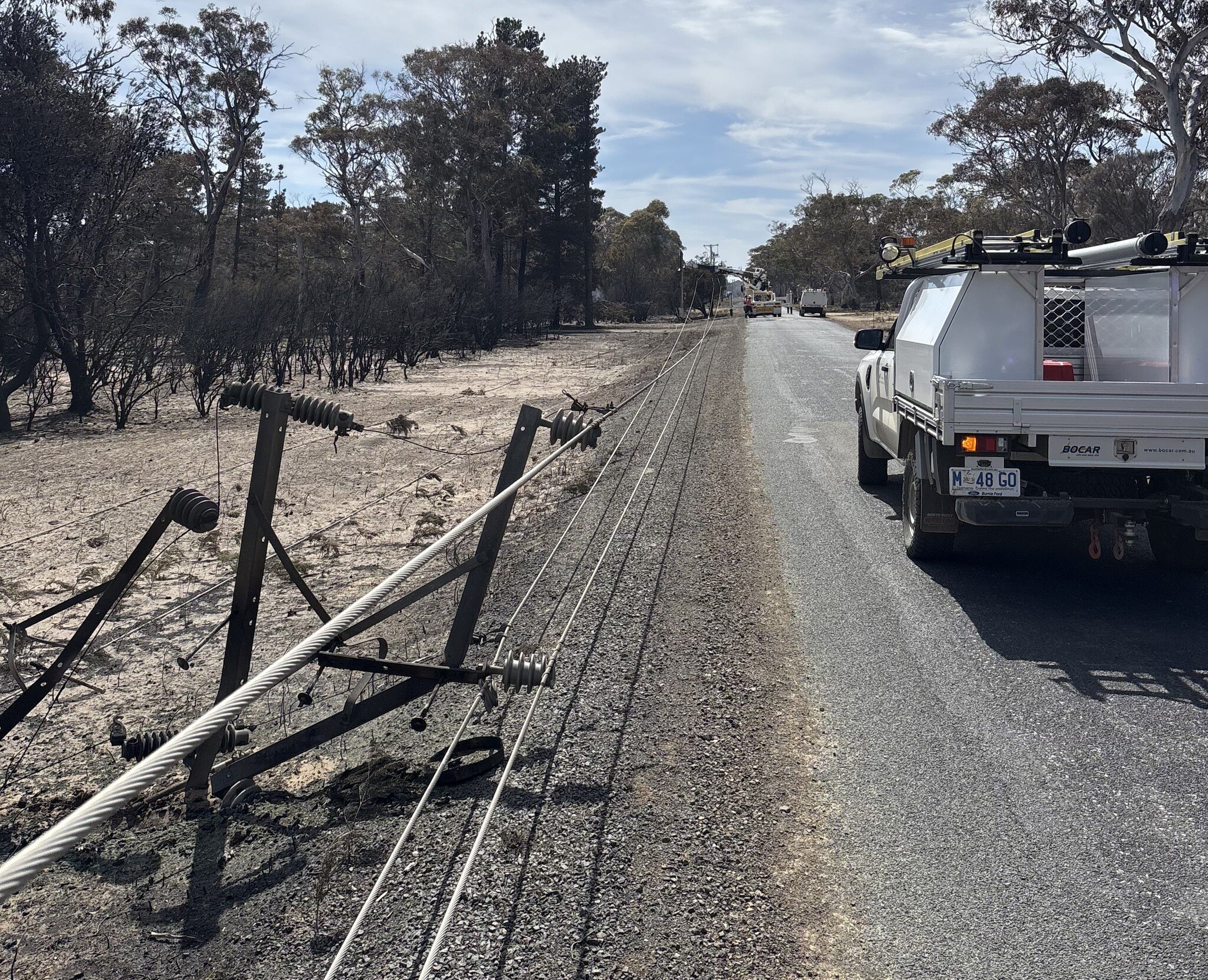 Daños por incendios forestales a líneas eléctricas en una carretera rural.