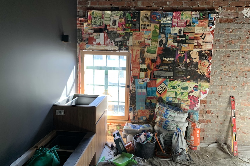 A room under renovation with old posters on the brick wall