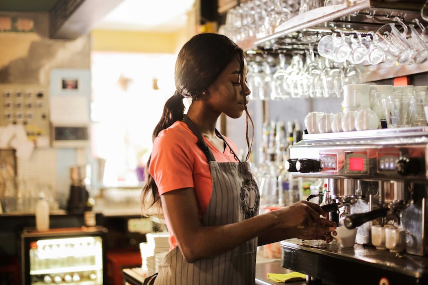 Woman making coffee in a cafe in a story about what is and isn't workplace bullying.