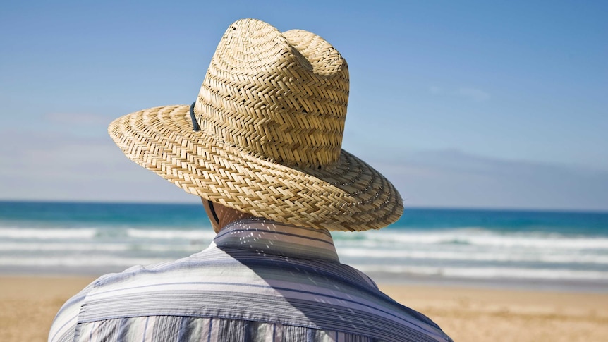 Man wearing straw hat on beach, Victoria, Australia